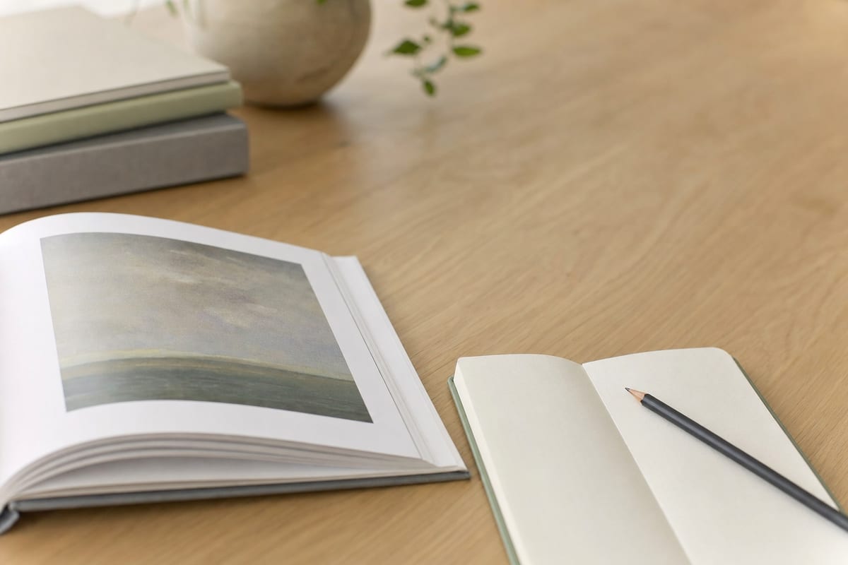 Art Essay — exhibition catalogue open at a plate, a notebook of observations and a pencil